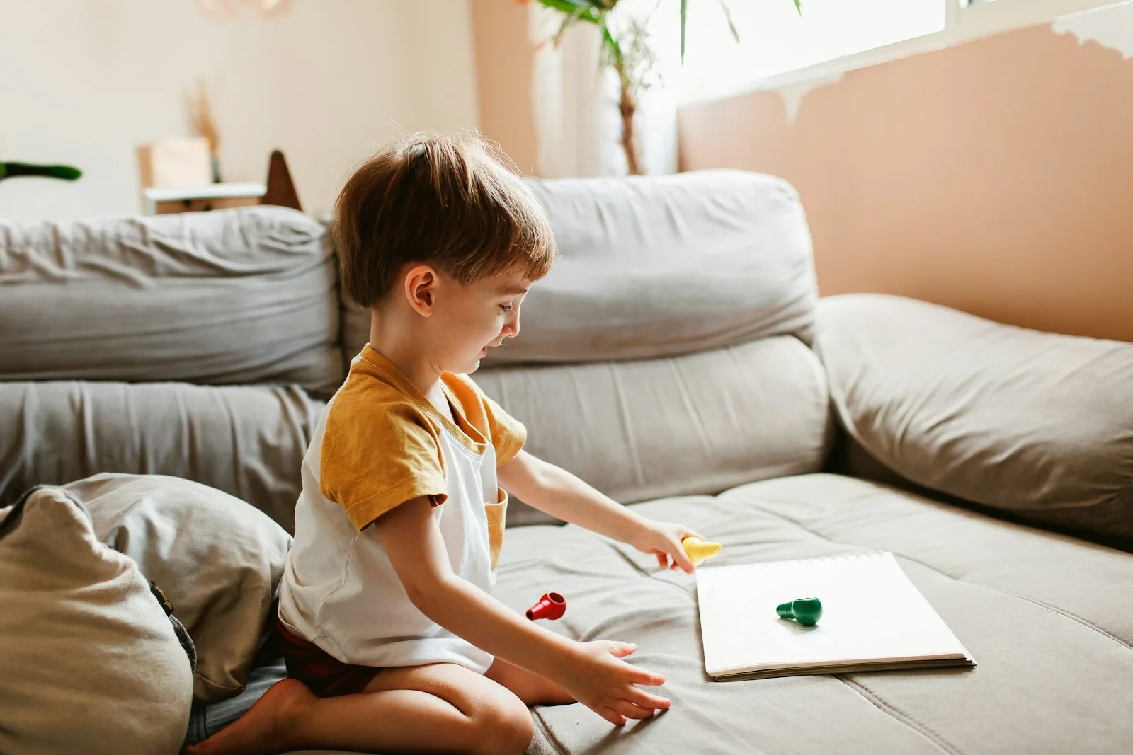 A young child quietly looking at a book on a couch.